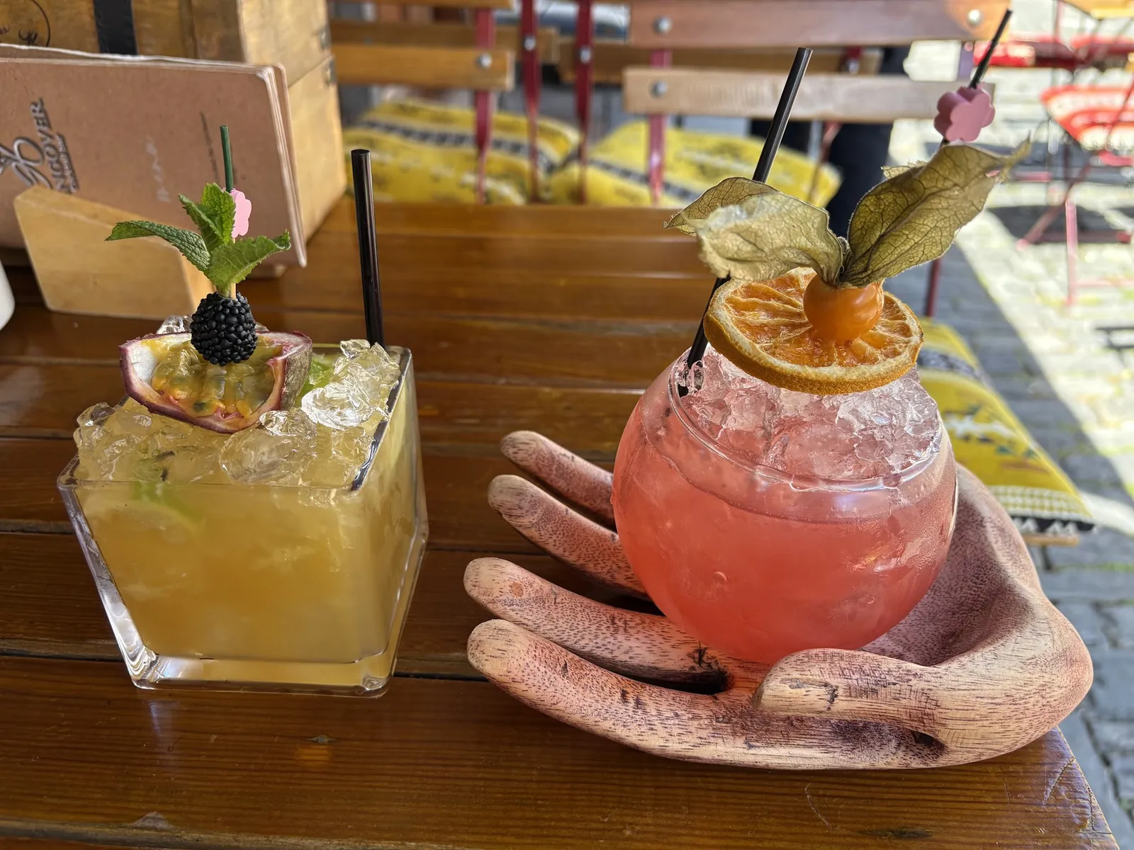 Two cocktails served on a carved wooden hand tray