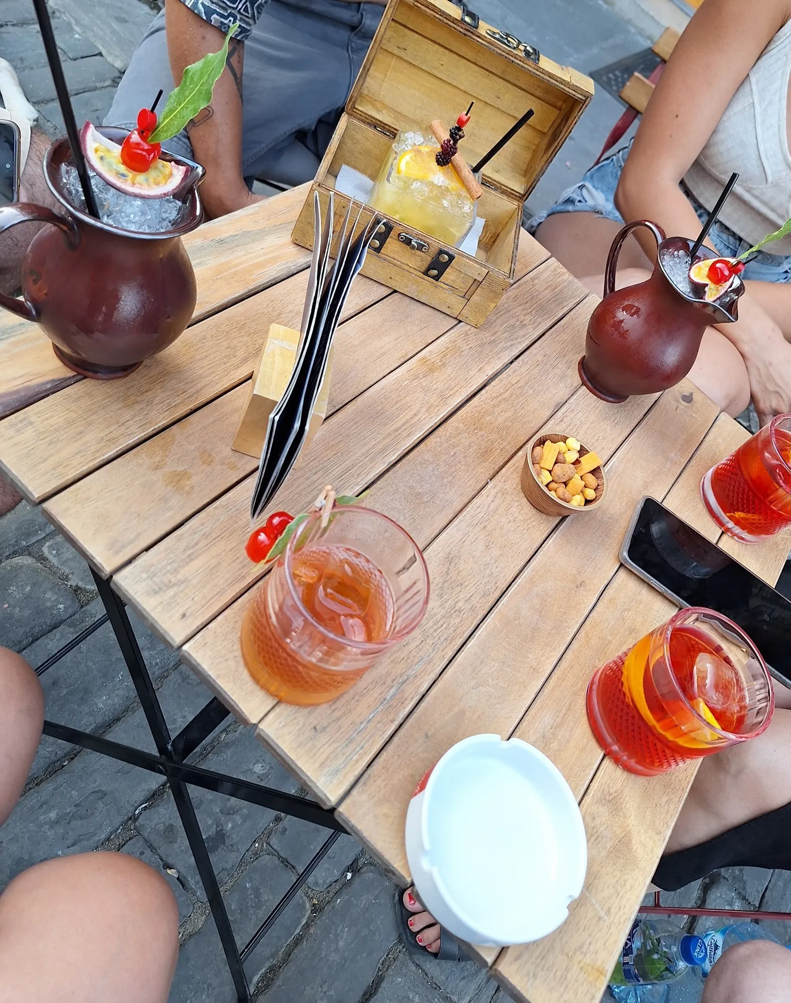 Cocktails on a wooden table on the cobblestones outside the bar